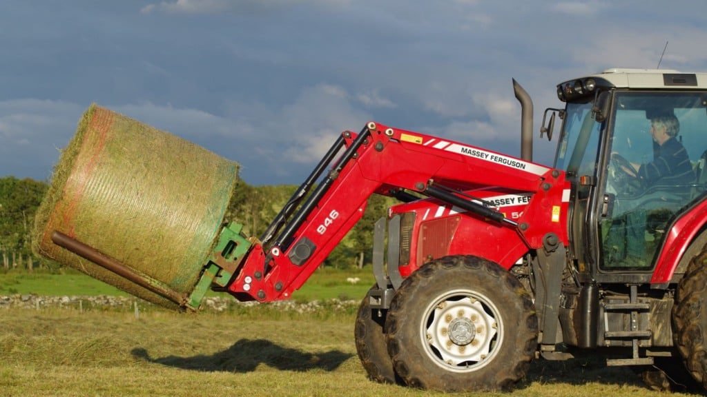 Trator com rolo de feno pela pastagem. Foto: Canva